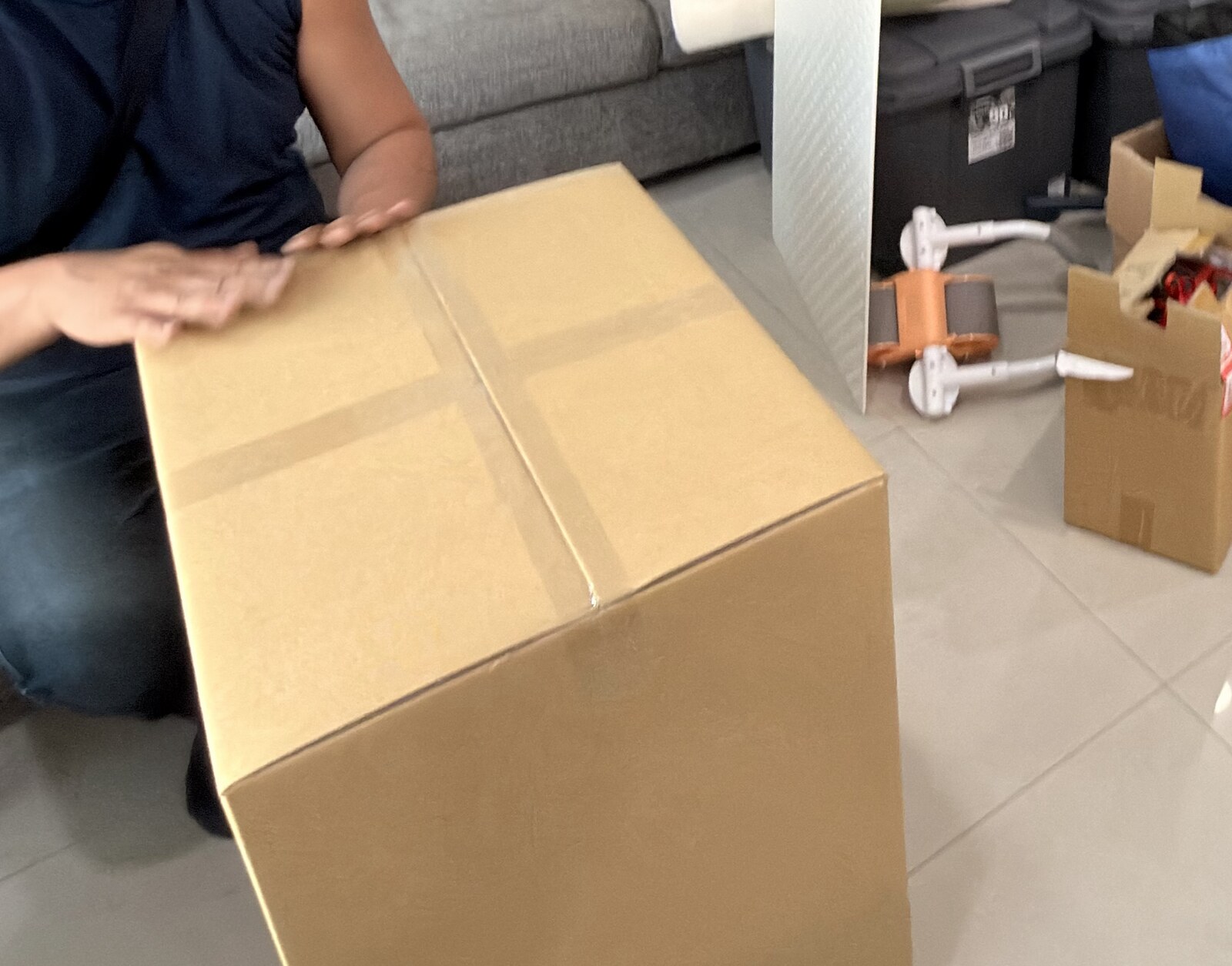 封箱的手，膠帶在紙箱上貼出十字